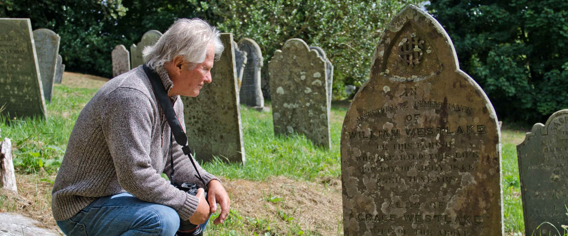 A guest looking at the headstone of his ancestor